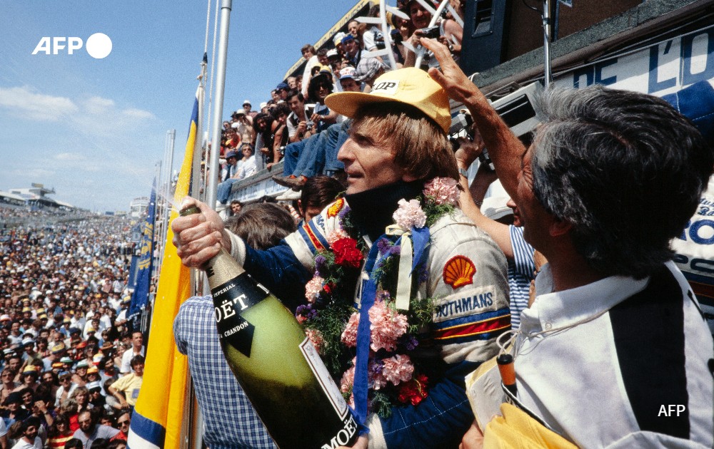 The Rothmans Porsche team drivers British Derek Bell sprayS champagne from the podium, 1982