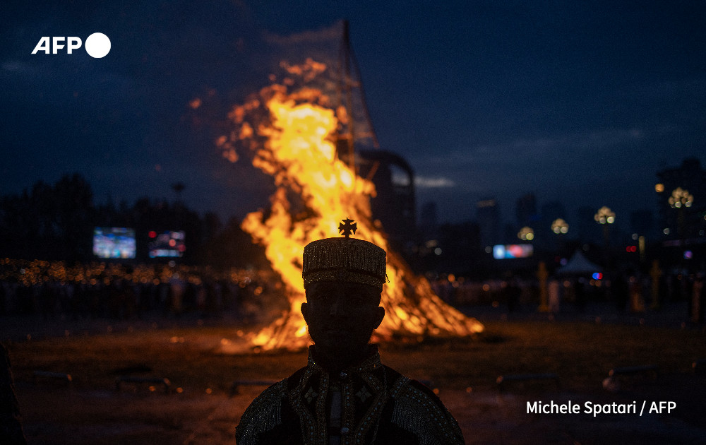 A priest stands in front of a bonfire during celebrations