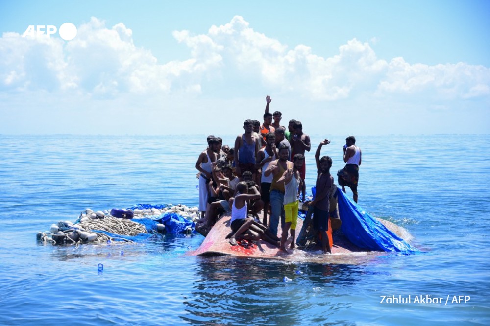 Rohingya refugees wait to be rescued from the hull of their capsized boat as a National Search and Rescue Agency (BASARNAS) vessel approaches 