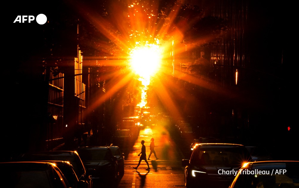 People croos a street at sunset