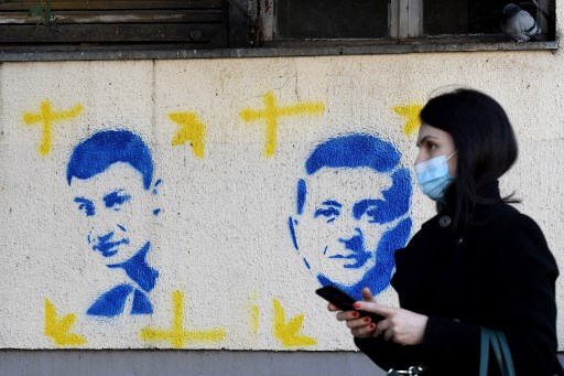 Une femme passe devant des peintures au pochoir représentant le maire de Kiev, Vitali Klitschko (G), et le président ukrainien, Volodymyr Zelensky, sur un bâtiment du centre-ville de Podgorica, le 9 mars 2022.