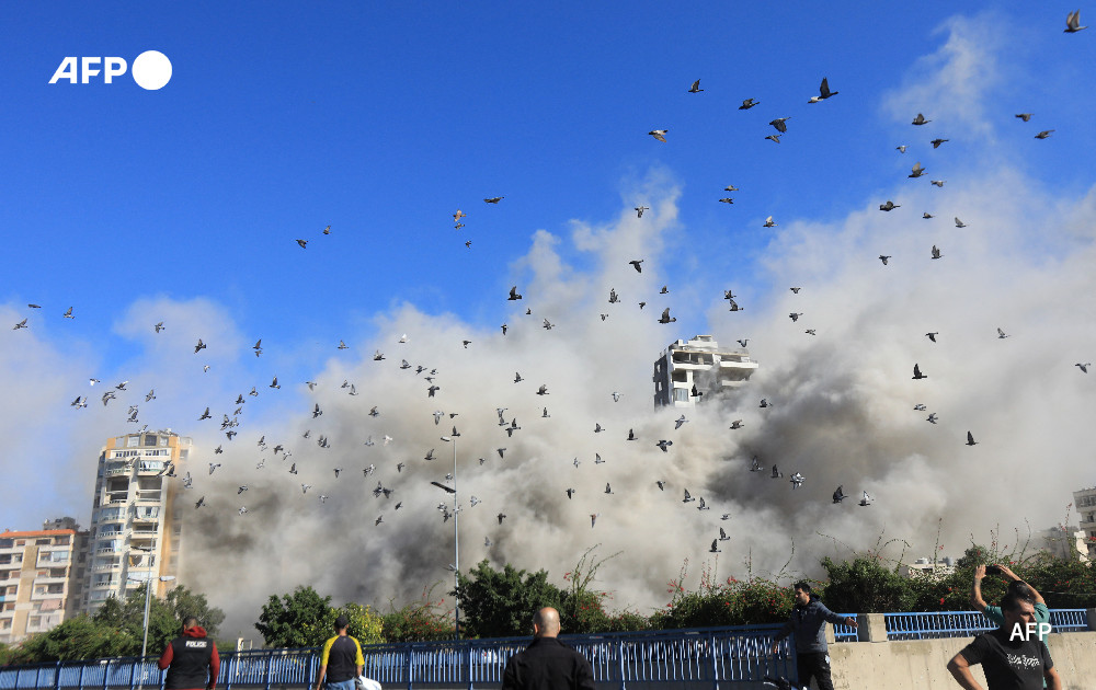 A flock of pigeons flies past a rising smoke cloud after an Israeli airstrike targeting Beirut's southern suburb of Shayah on October 22, 2024