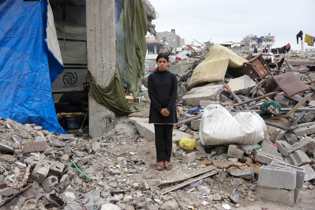 Maram Al-Assali, 12, poses in front of her destroyed home in Jabalia