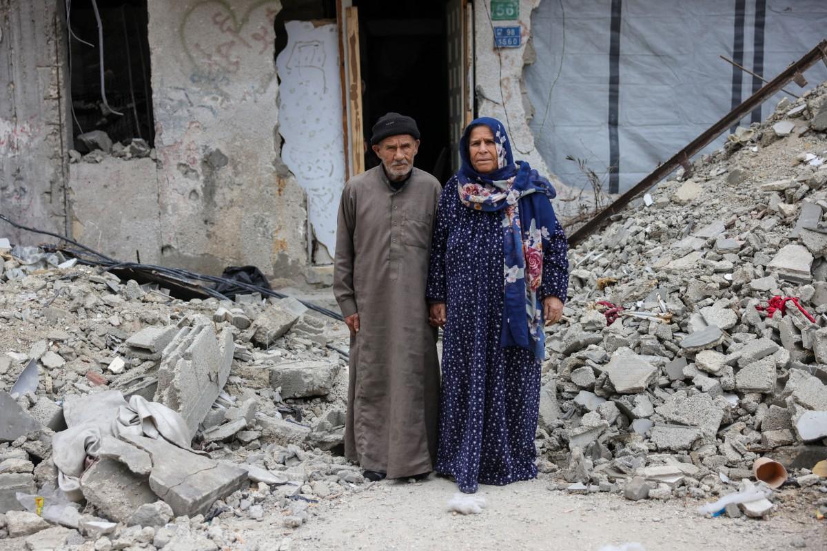 Mohammed Ghneim, 84, and his wife Aisha, 71, pose in front of their destroyed home in Jabalia