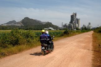 Cette photo montre des travailleurs circulant en moto près de l'usine de ciment Chip Mong Insee dans la province de Kampot. © Tang Chhin Sothy / AFP