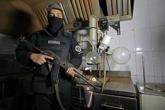 A member of the security forces of the new Syrian authorities stands guard next to equipment used to manufacture drugs